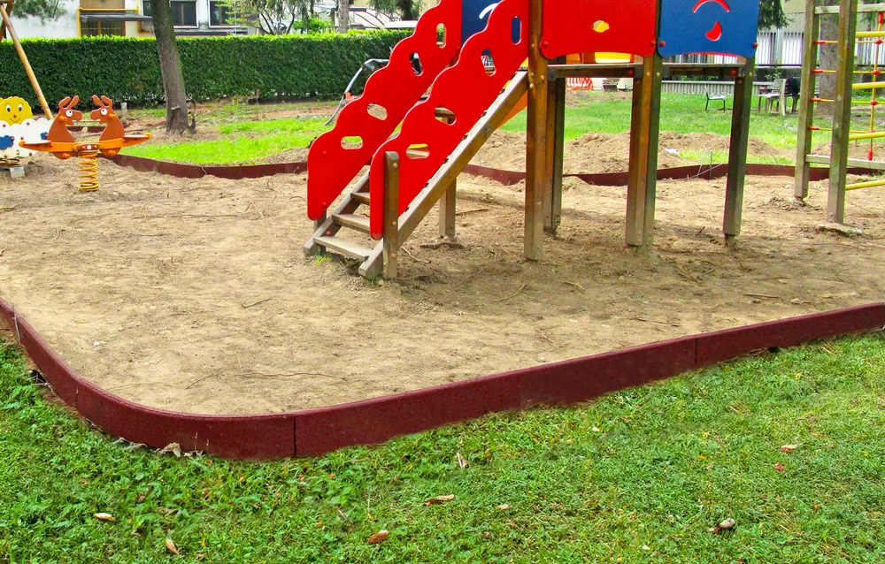 ECO-FUN 19 Rote ECO-BORDER-Randsteine, die entlang der Begrenzung eines Spielplatzes verlegt wurden